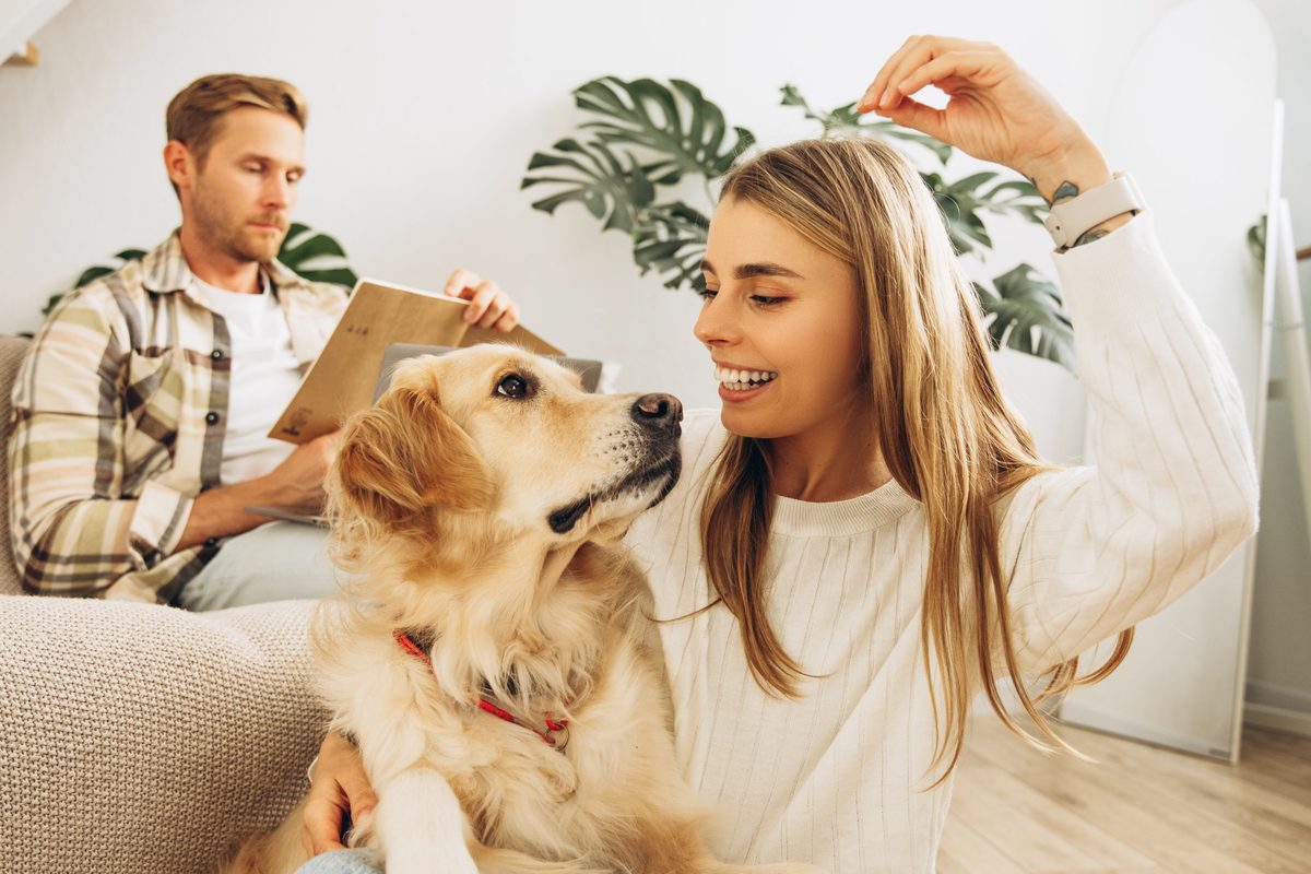 Mulher sorrindo ao lado de um cachorro golden retriever em casa