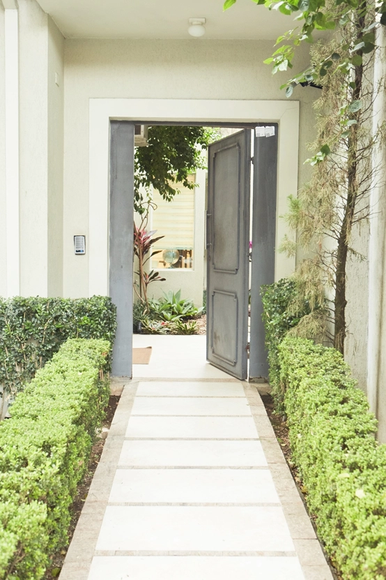 Entrada da clínica, com portão aberto e caminho de pedra entre jardins