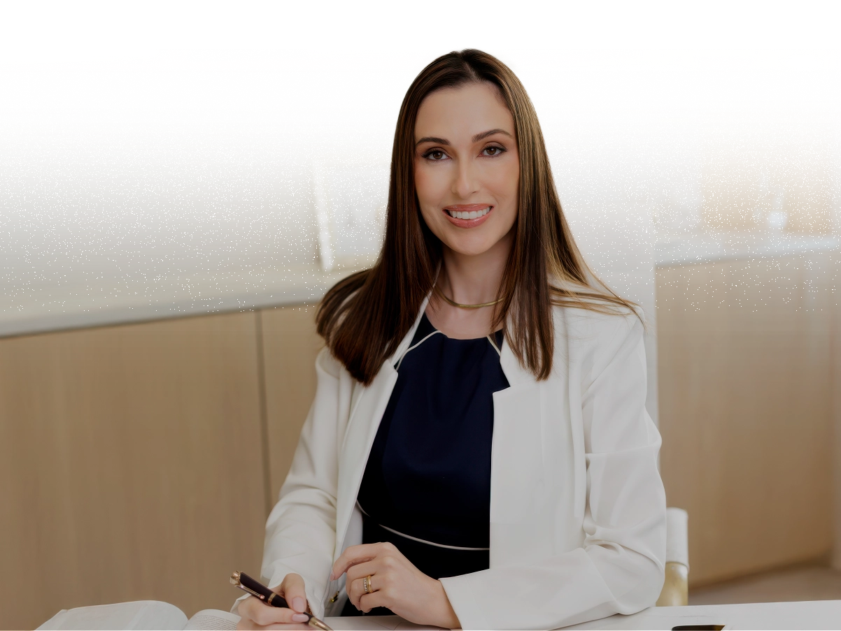 Dra. Marina Biella, médica geriatra e clínica médica, sorrindo à mesa de seu consultório